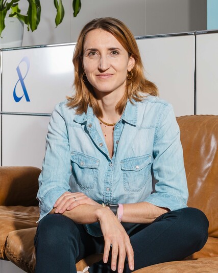 Julia Batzlen-von Bank sits on a brown leather sofa.