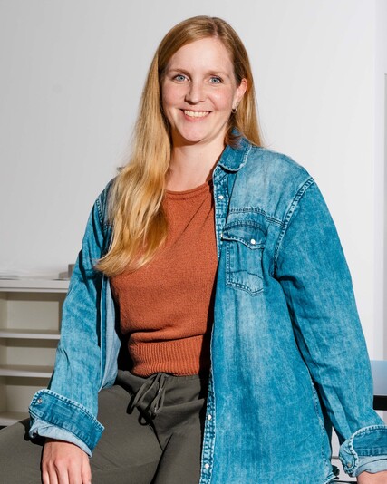 Swetlana Bregy leans smiling against a bookshelf.