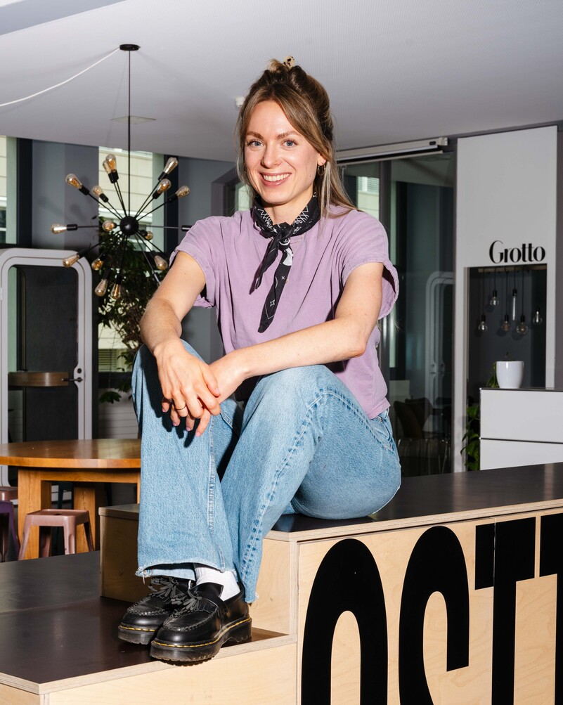 Lea Züllig sits on a wooden fixture in the office kitchen.