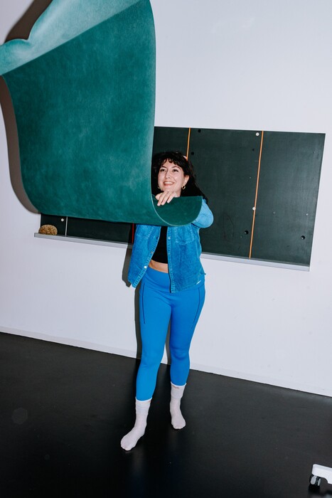 A colleague carries a large turquoise upholstered piece across the room.