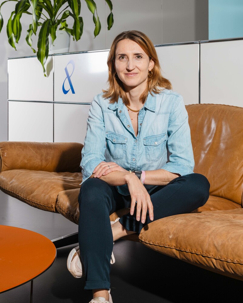 Julia Batzlen-von Bank sits on a brown leather sofa.