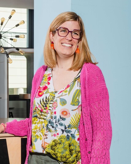 Julia Weber stands smiling beside a wooden office fixture.