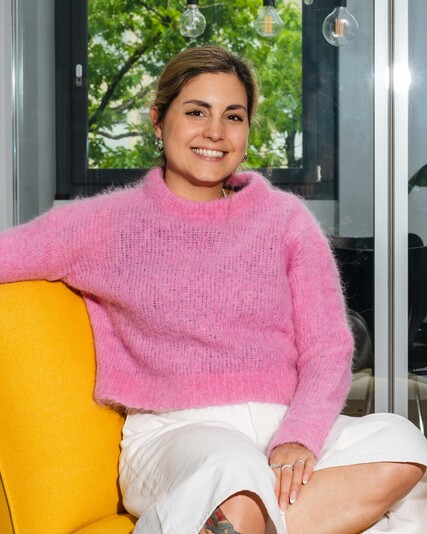 Marcella Franzé sits smiling on a yellow armchair.