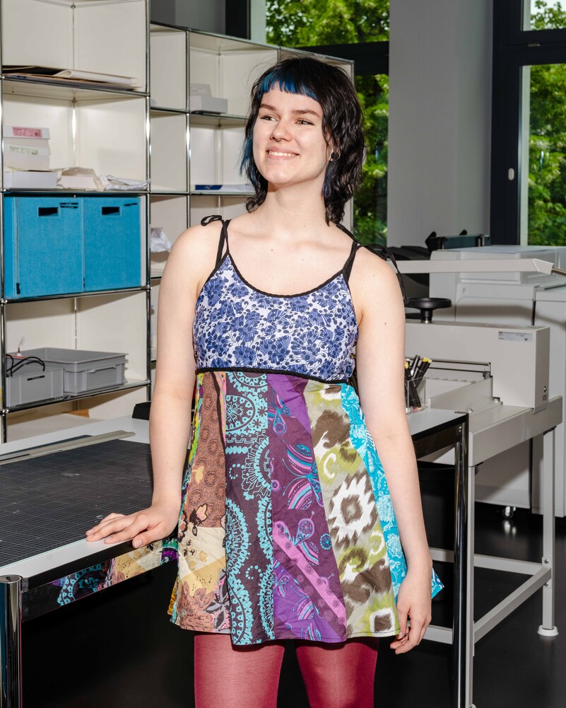 Polya Afanasyeva stands smiling beside a production worktable.