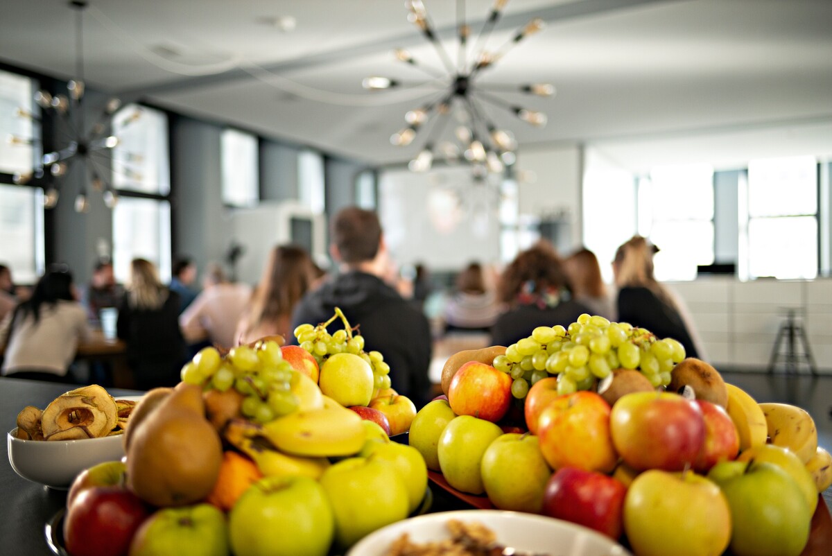 Bowls of fresh fruit stand in front of a gathered group.
