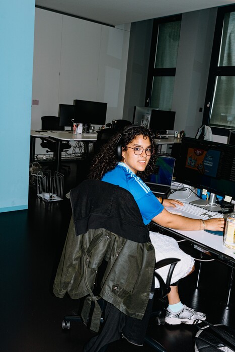 A colleague turns towards the camera at her workstation.