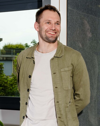 Leon Schulte stands smiling beside an acoustic work booth.
