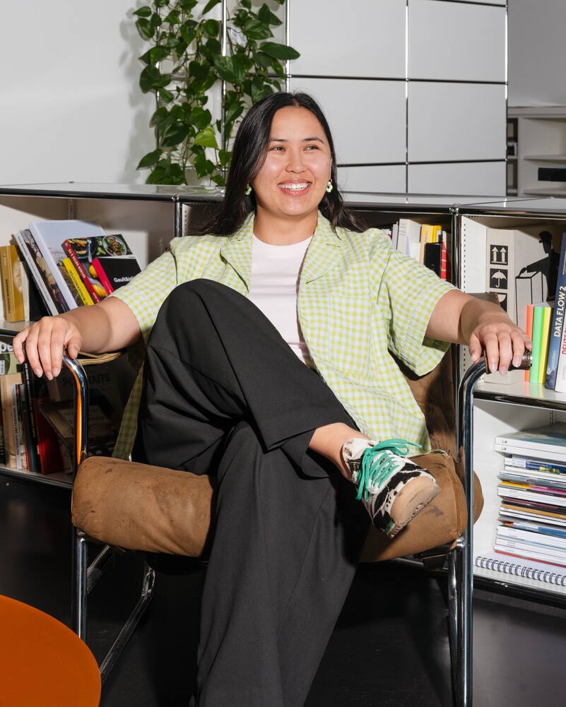 Desirée Lanz sits smiling in a leather armchair in front of bookshelves.