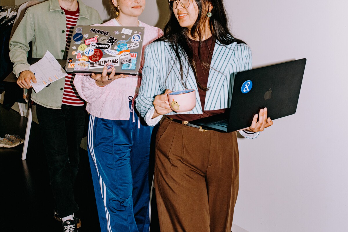 Three team members carry laptops, documents and a cup.