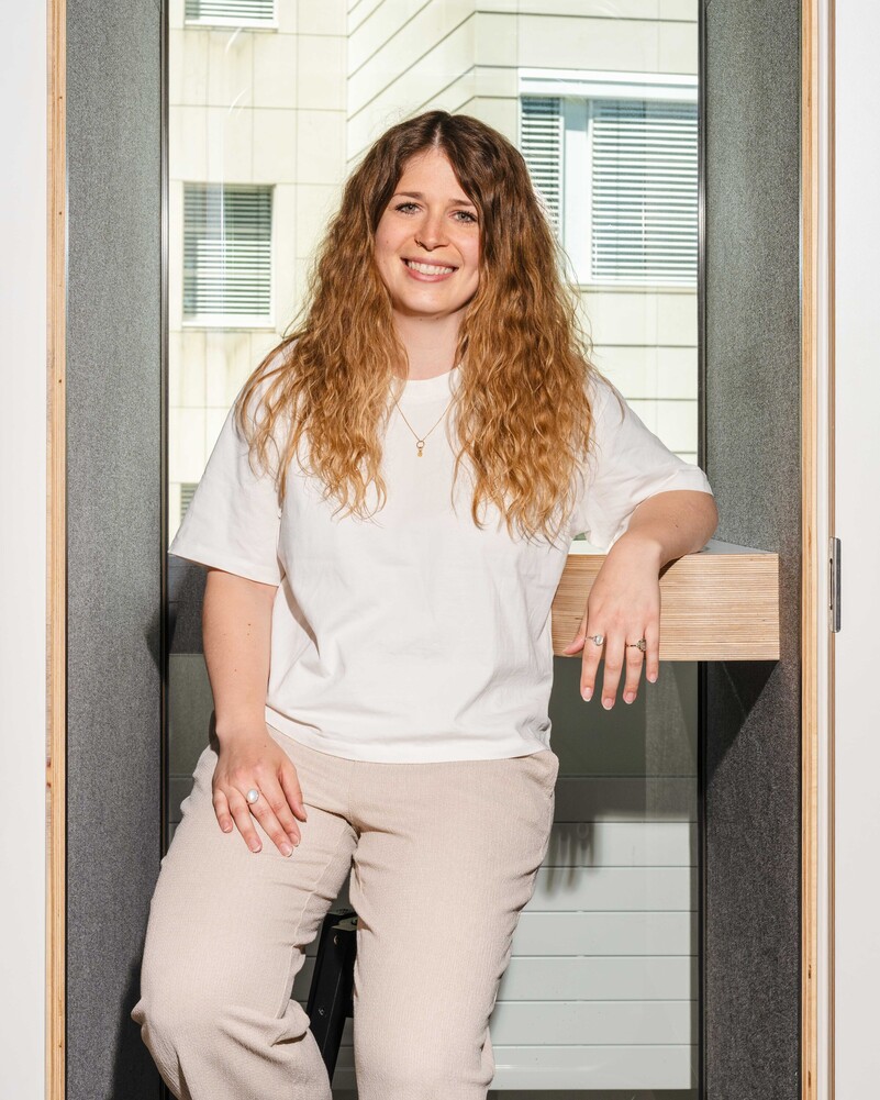 Michelle Honegger stands smiling inside a work booth.
