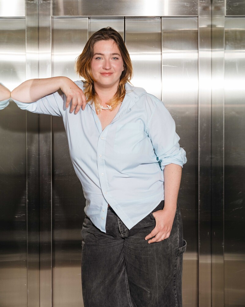 Aline Meister leans against the metal wall of a lift.