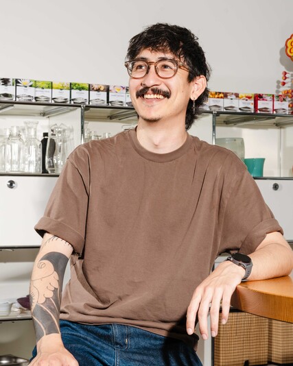 Dominic Schweingruber sits smiling at a table in the office kitchen.