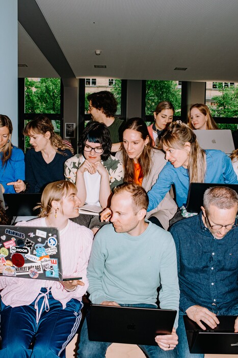 A large group works closely together with several laptops.