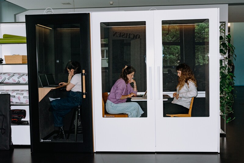 Three team members work in adjacent office booths.