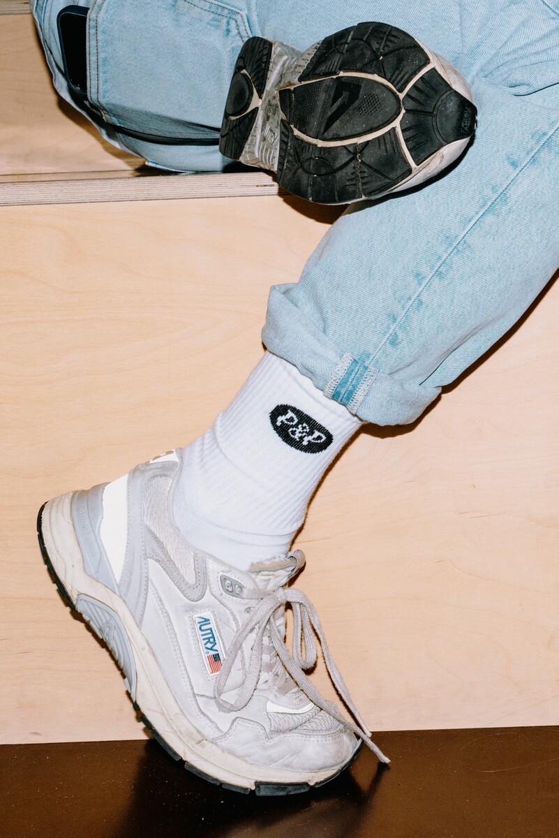 Jasmina Seelig sits with her legs crossed, with her trainers shown in close-up.