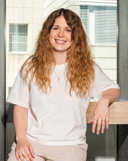 Michelle Honegger stands smiling inside a work booth.