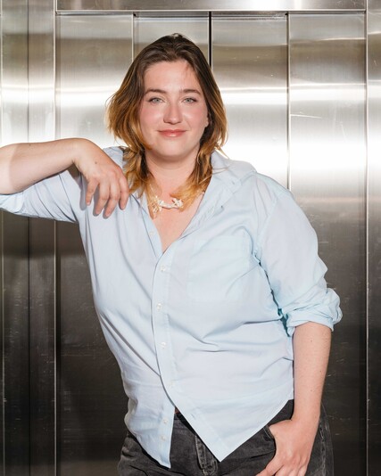 Aline Meister leans against the metal wall of a lift.