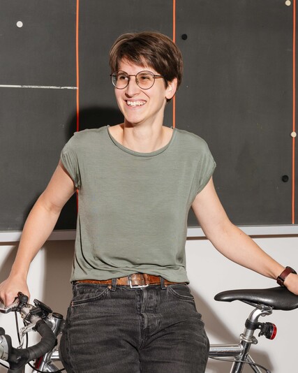 Bettina Baumann stands smiling beside a road bicycle.