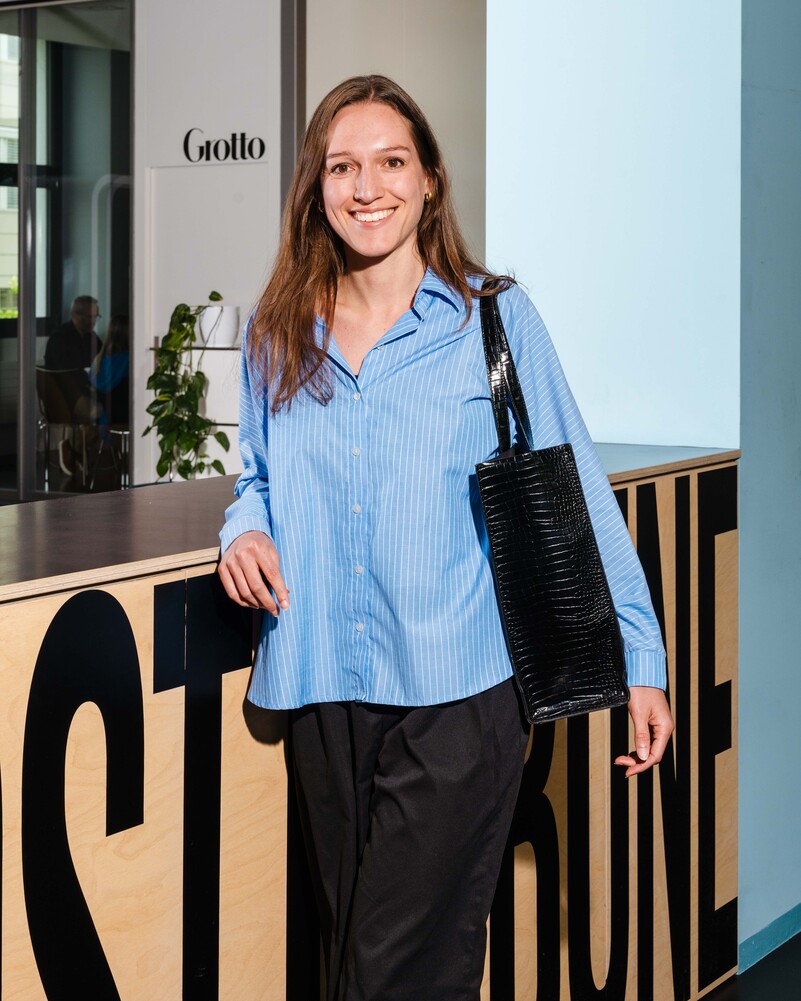 Salome Bartolomeoli stands smiling in the office with a black bag.