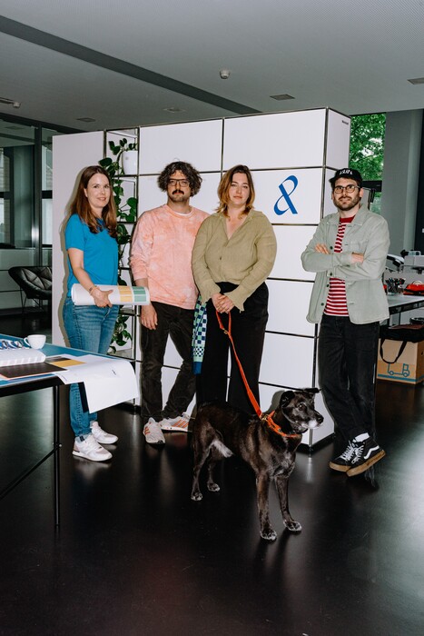 Four team members stand with a dog in front of the company symbol.