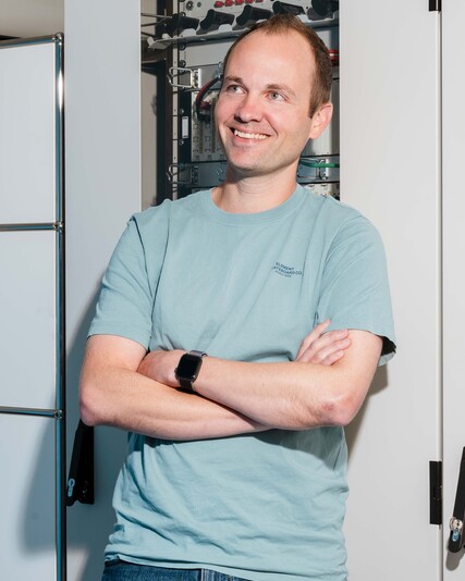Patrick Haas stands with his arms crossed in front of a server rack.
