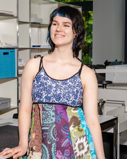 Polya Afanasyeva stands smiling beside a production worktable.