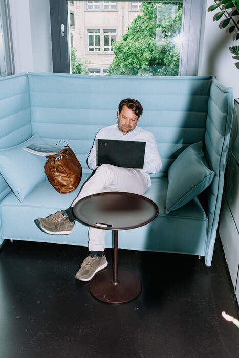A team member works on a laptop in a light-blue booth.