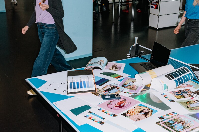 Designs, colour samples, magazines and a laptop lie across a table-tennis table.