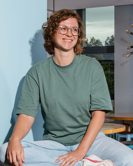 Charlotte Künzle sits cross-legged on a wooden platform in the office.