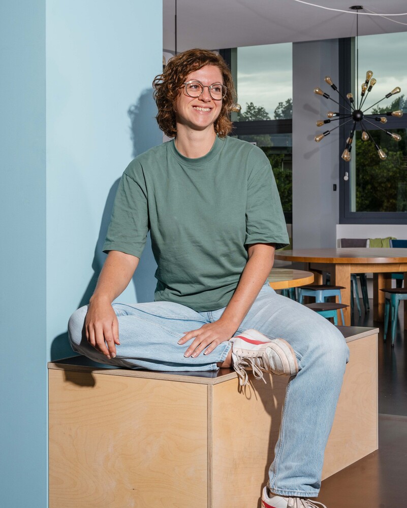 Charlotte Künzle sits cross-legged on a wooden platform in the office.