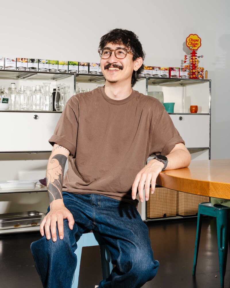 Dominic Schweingruber sits smiling at a table in the office kitchen.