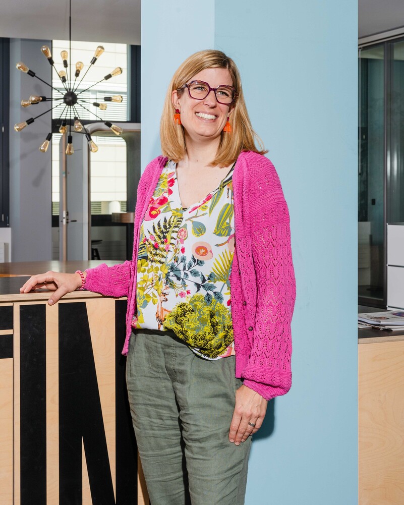 Julia Weber stands smiling beside a wooden office fixture.