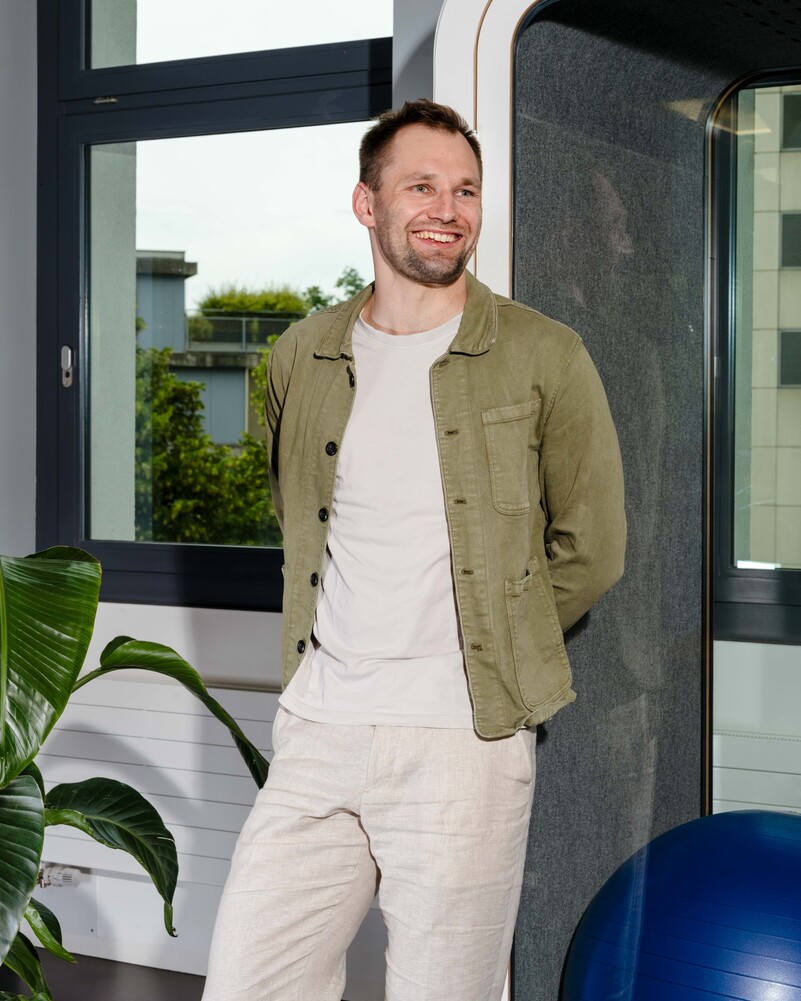 Leon Schulte stands smiling beside an acoustic work booth.
