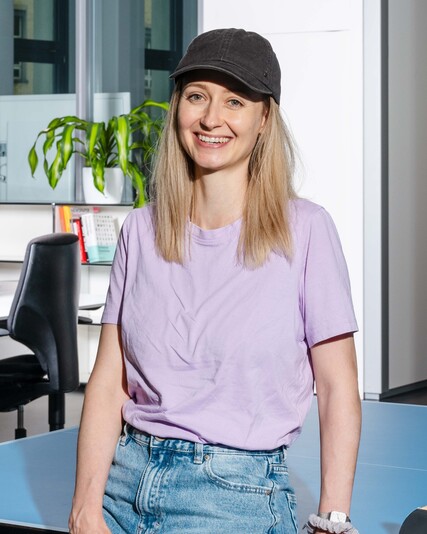 Dominique Martin stands at a table-tennis table holding a paddle.