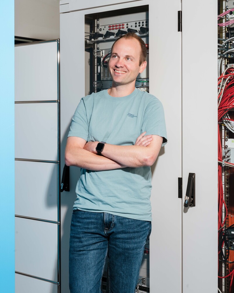 Patrick Haas stands with his arms crossed in front of a server rack.