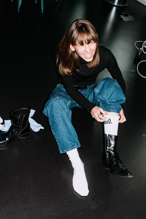 A colleague sits on the floor and pulls on a black boot.